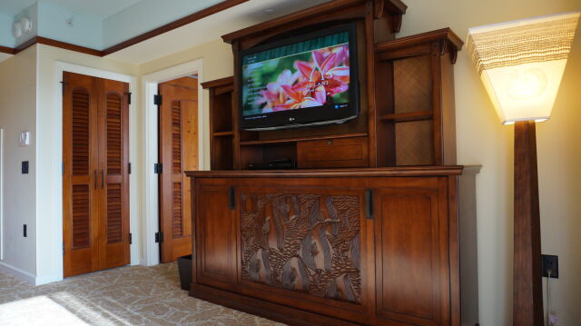Warm wood suite with TV armoire, elegant lighting, and ample storage