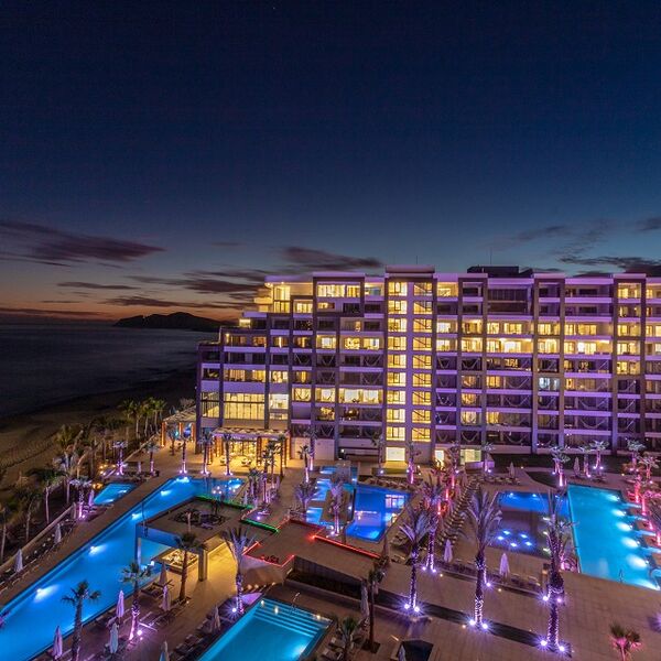 Beachfront resort at dusk with glowing pools and stunning coastal views