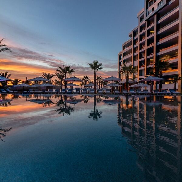 Resort-style pool oasis with sunset views, palms, and elegant lounge seating