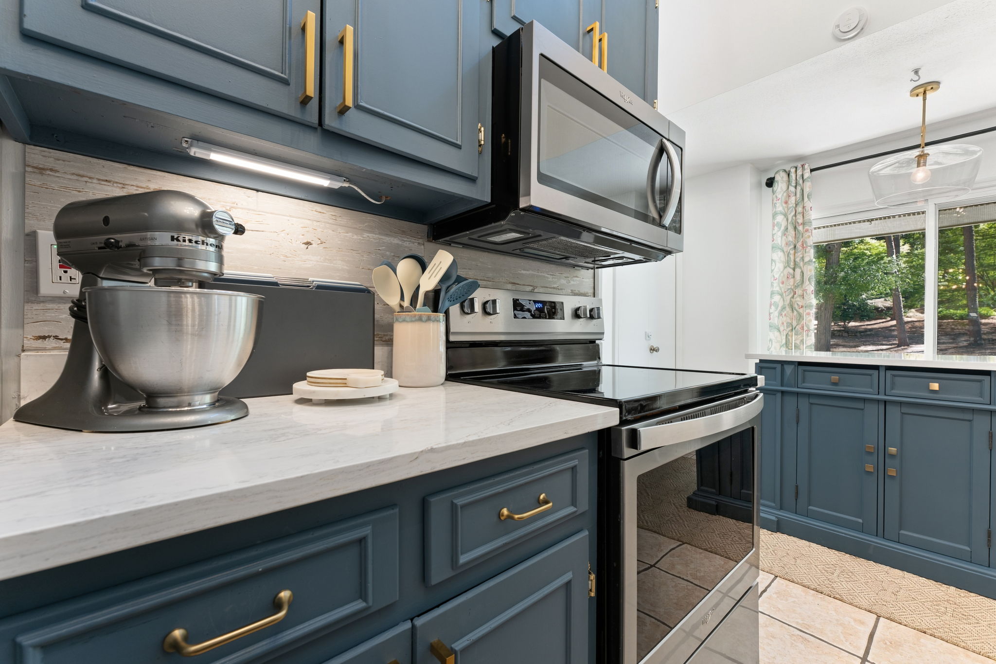 Everything a cook needs: marble counters, blue cabinetry, a KitchenAid mixer, and a view that won't quit.