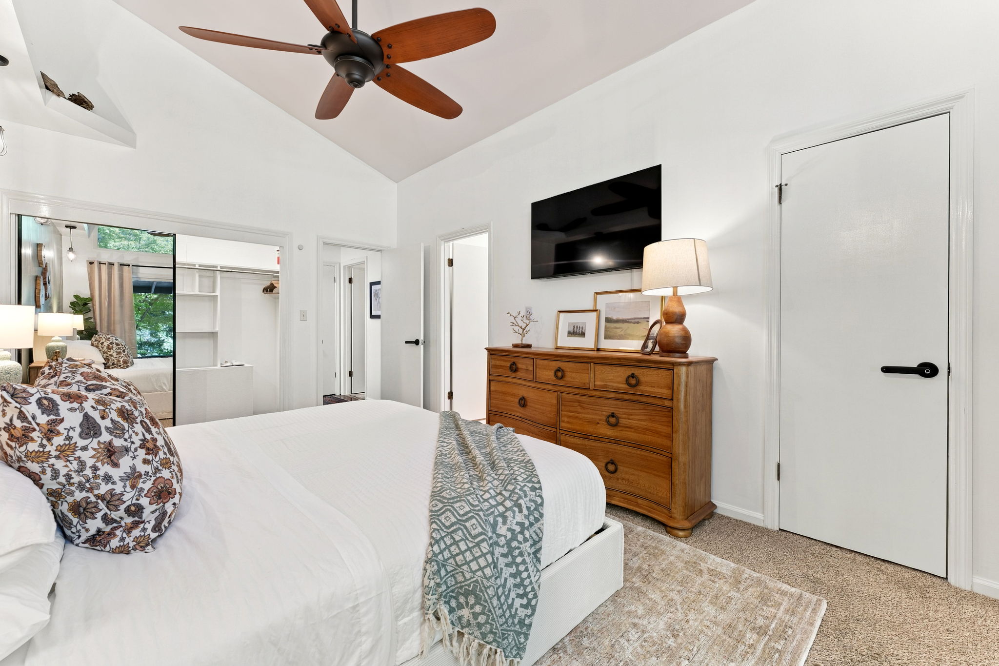 Bright vaulted bedroom with TV, ceiling fan, and spacious closet area