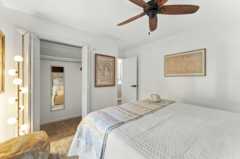 Bright, cozy bedroom with ceiling fan, full-length mirror, and closet space