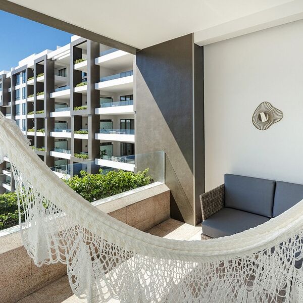 Relax on a private balcony with hammock seating and modern resort views