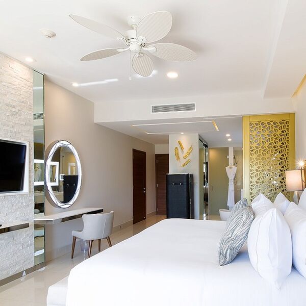 Bright, modern bedroom with plush bedding, vanity, and elegant design