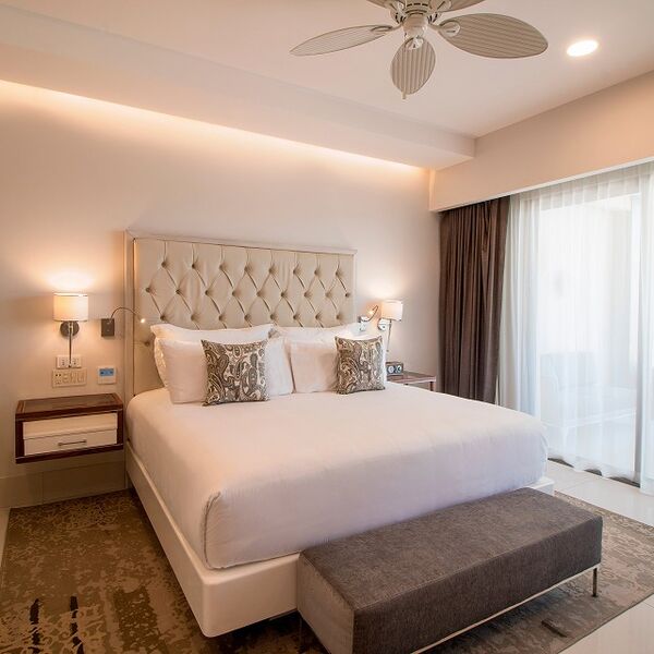 Elegant king bedroom with tufted headboard and bright balcony doors