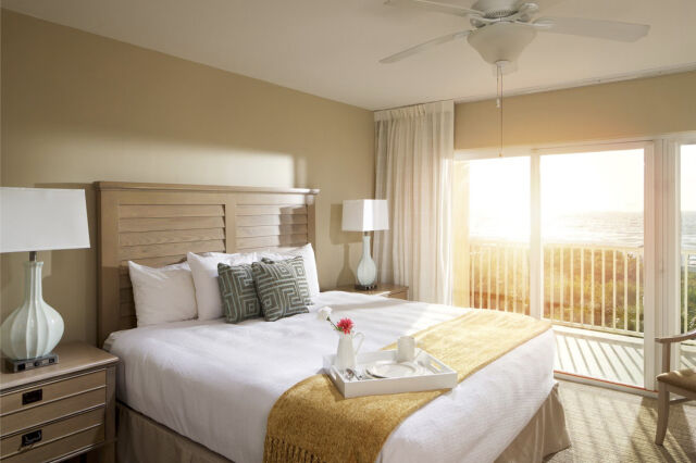 Sunlit bedroom with private balcony and serene outdoor views