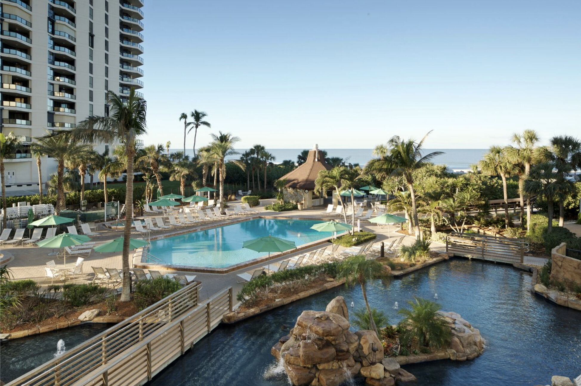 Resort-style pool oasis with tropical views and a glimpse of the ocean