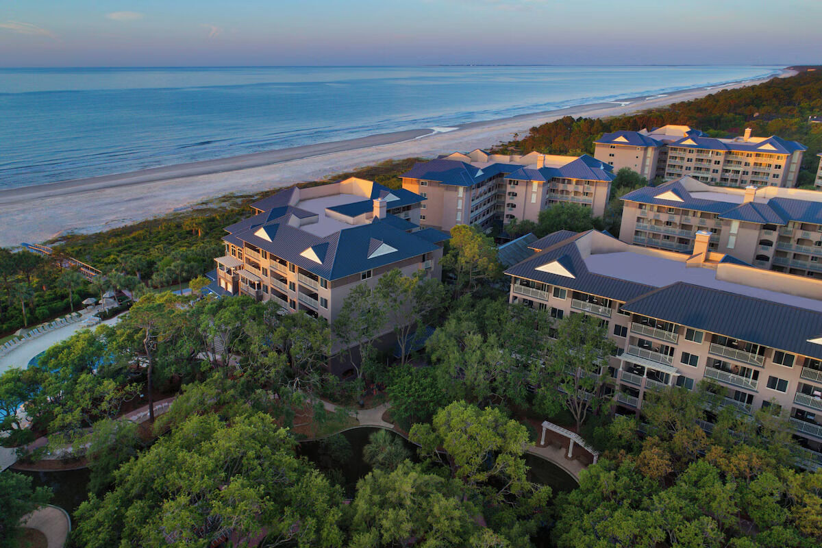 Aerial view of beachfront resort surrounded by lush greenery and ocean views