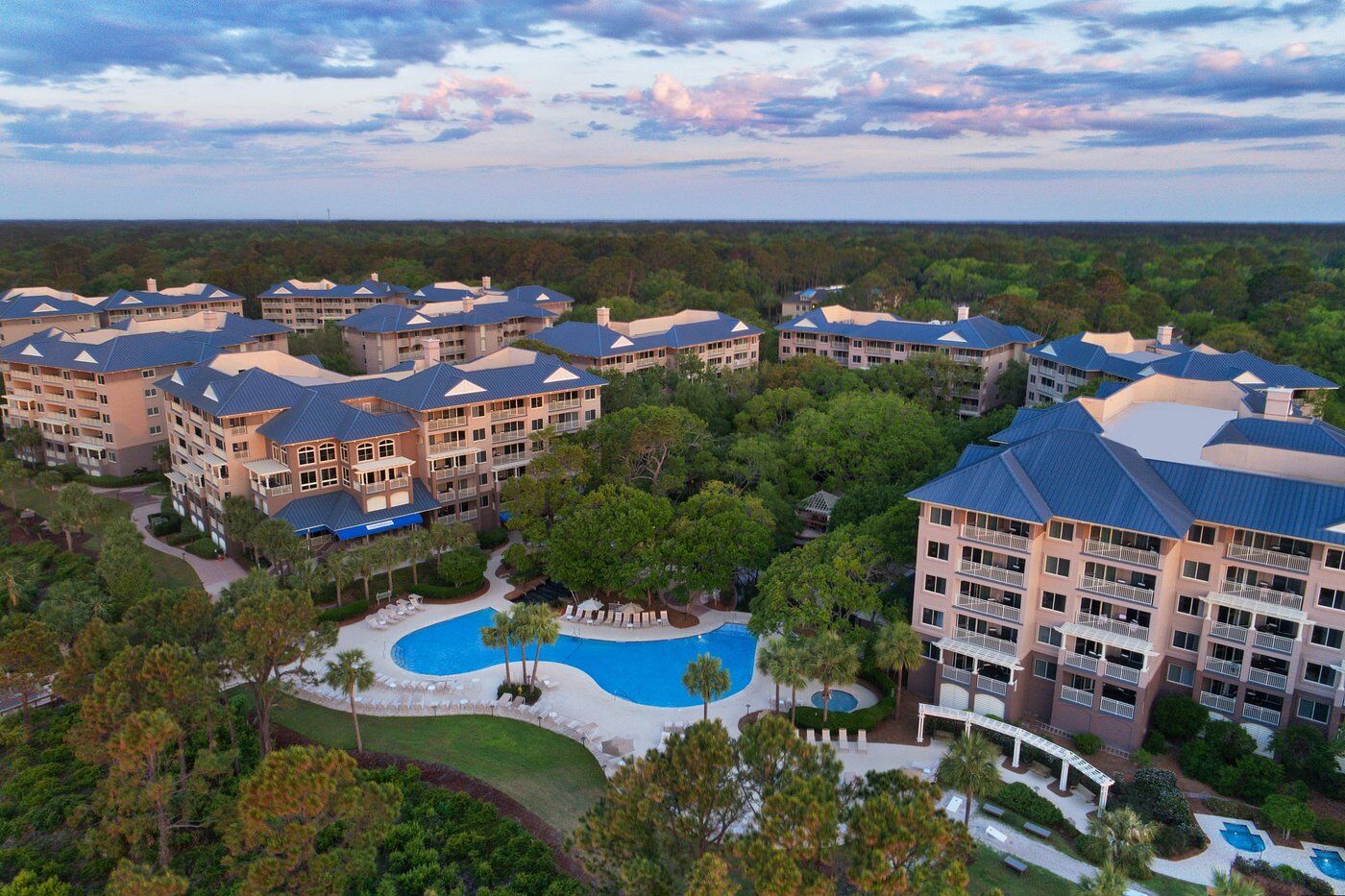 Aerial view of resort-style condos with pool, balconies, and lush grounds