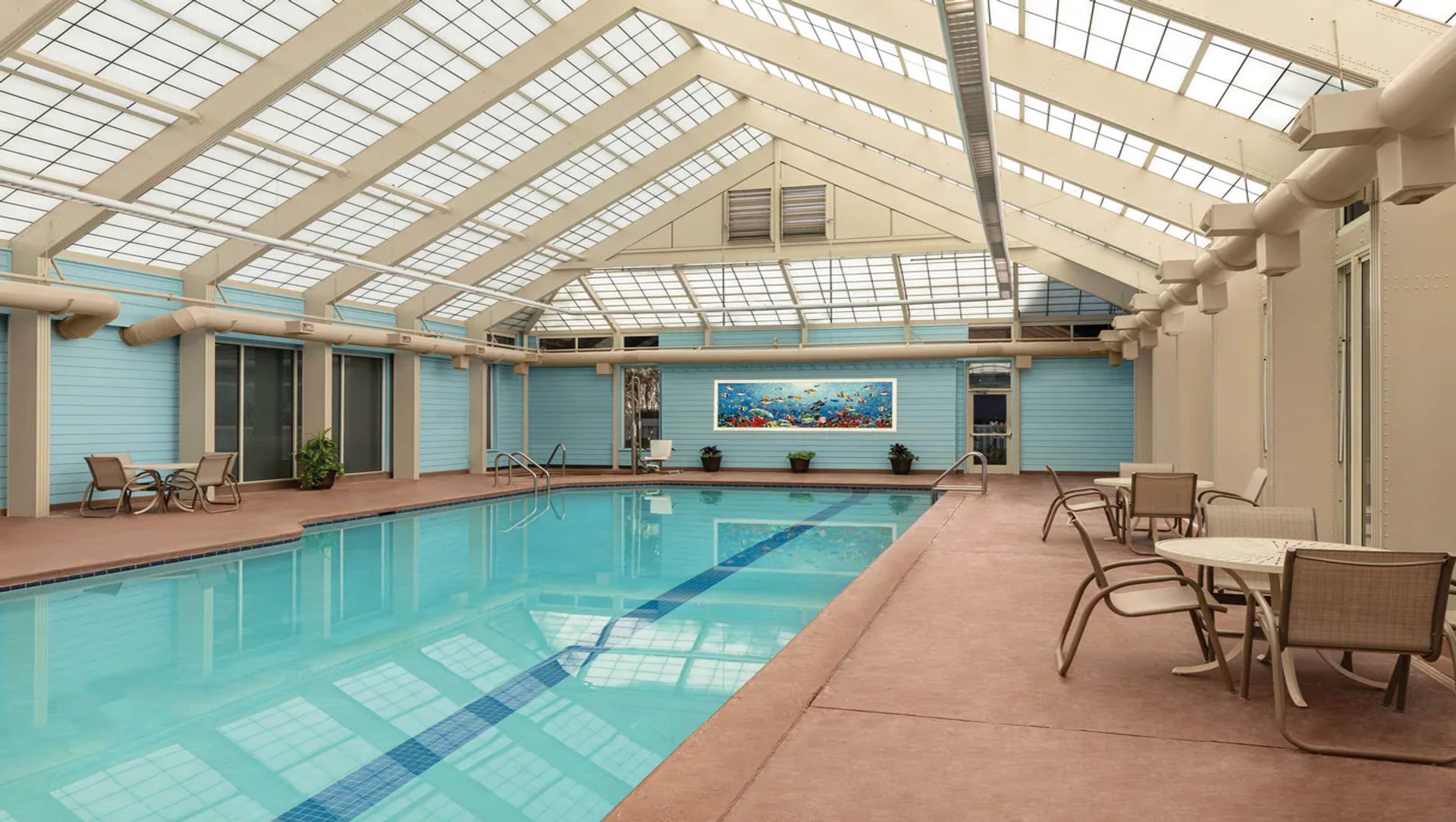 Bright indoor pool with skylit ceiling, lounge seating, and year-round appeal