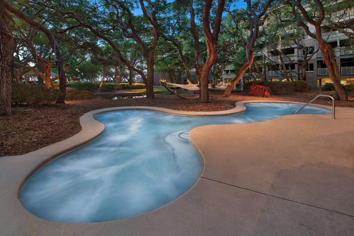 Relaxing lazy river pool surrounded by lush trees and resort-style grounds