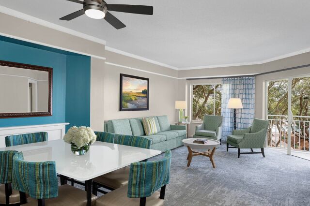 Bright coastal living room with balcony views and dining for four