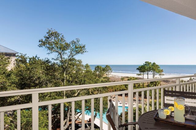 Private balcony with ocean views, outdoor seating, and pool glimpses