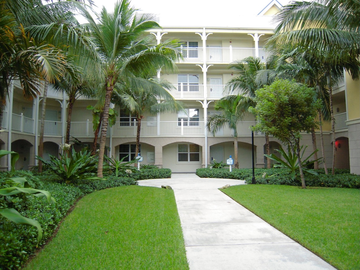 Resort-style courtyard with palms, lush lawns, and private balconies