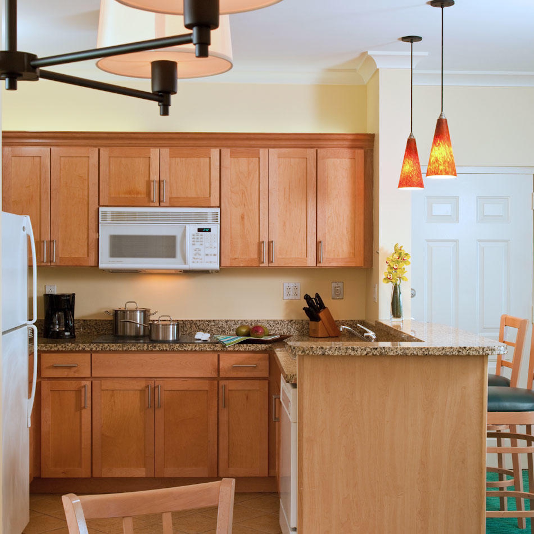 Bright kitchen with granite counters, breakfast bar, and warm wood finishes