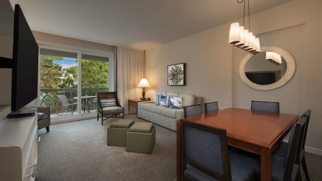 Bright living-dining space with private balcony and peaceful tree views