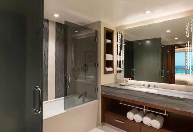 Modern spa-style bathroom with double vanity and sleek glass tub shower