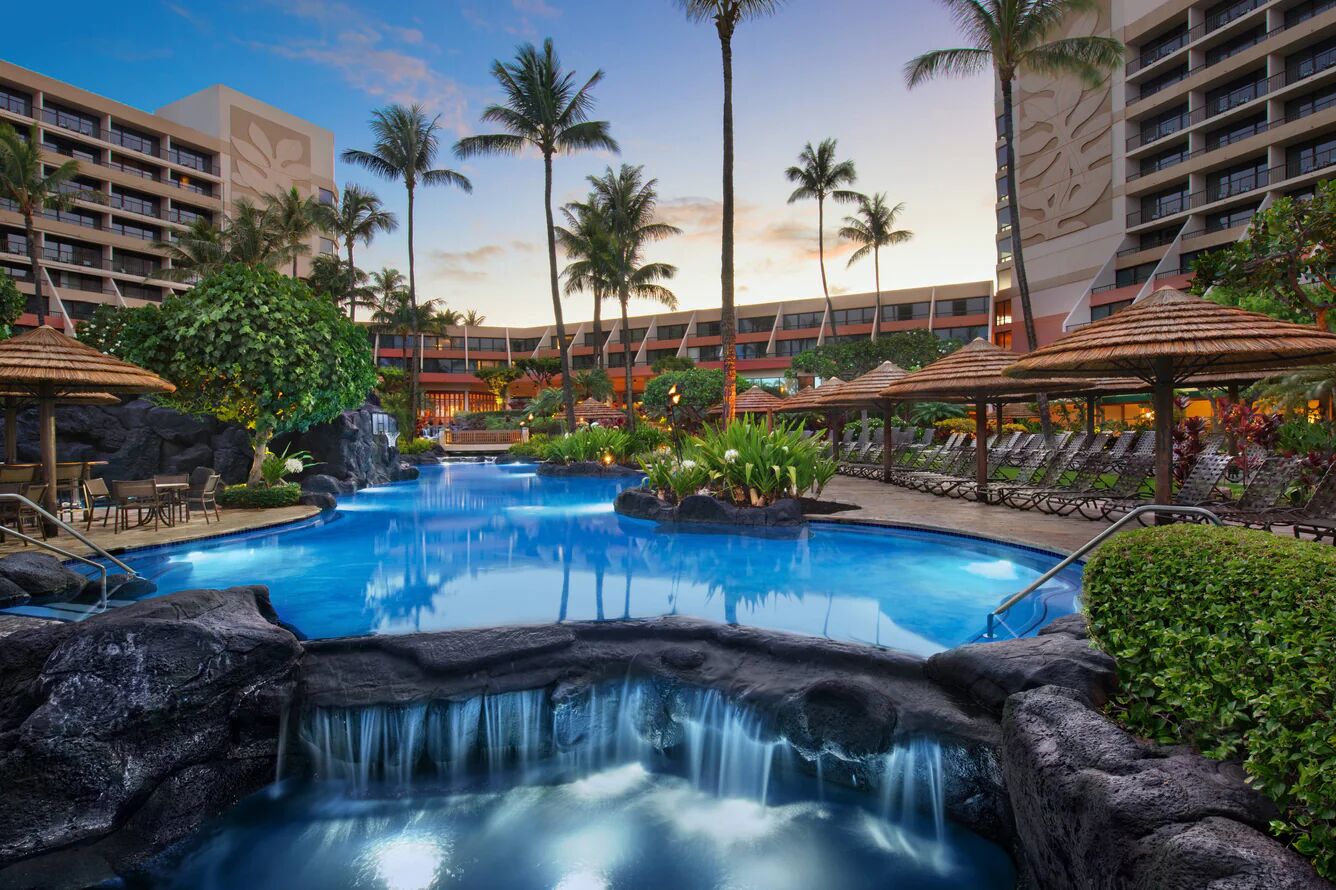 Tropical lagoon pool with waterfalls, palms, and relaxing resort-style seating