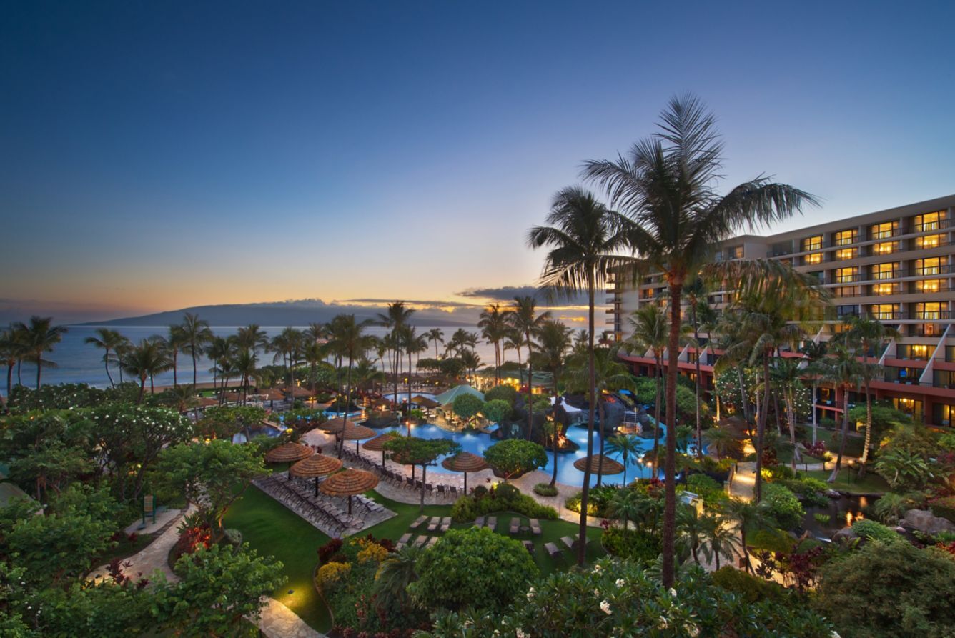 Tropical oceanfront resort with lagoon pools, palm trees, and sunset views