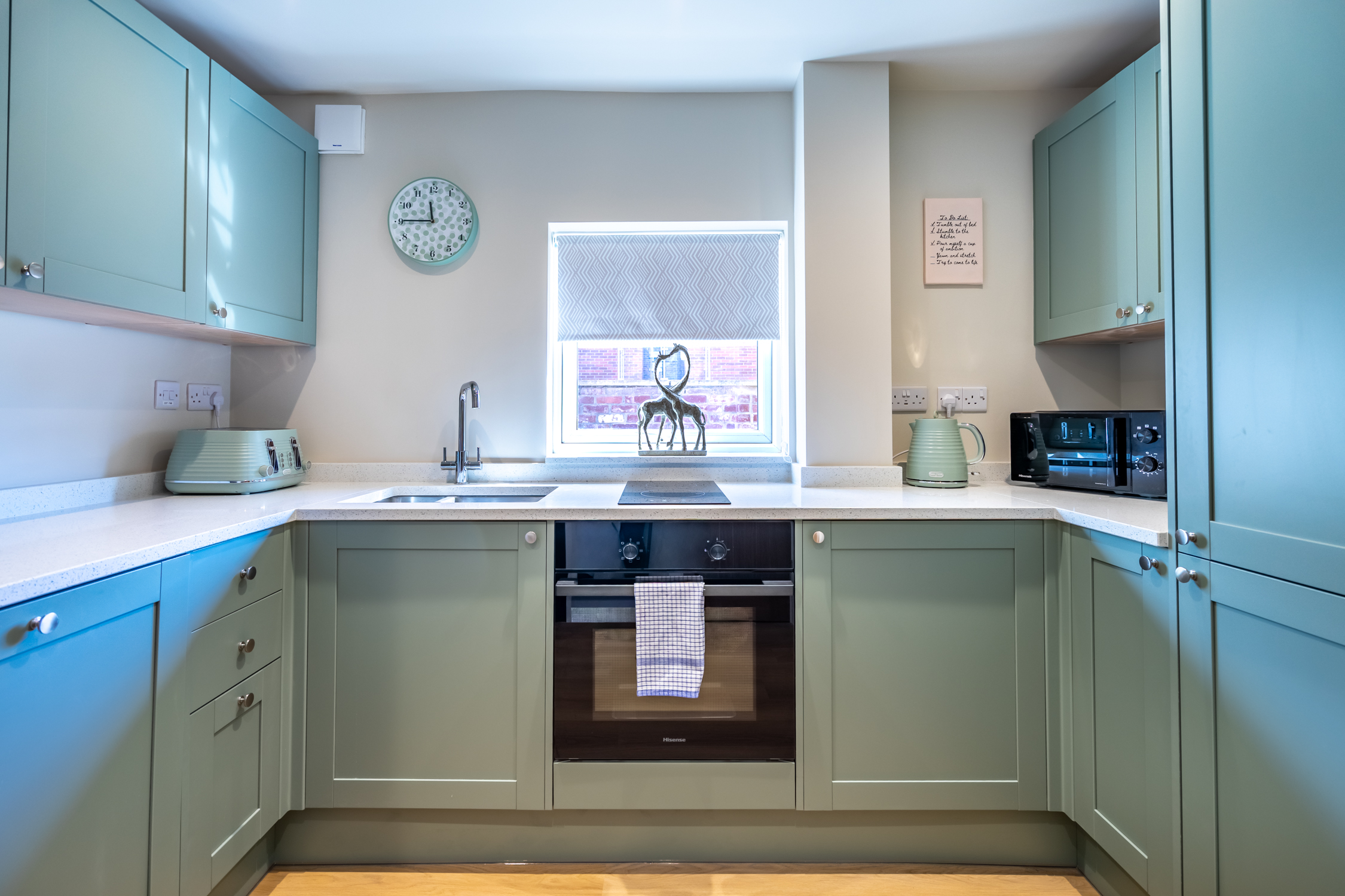 Bright sage-green kitchen with modern appliances and plenty of workspace