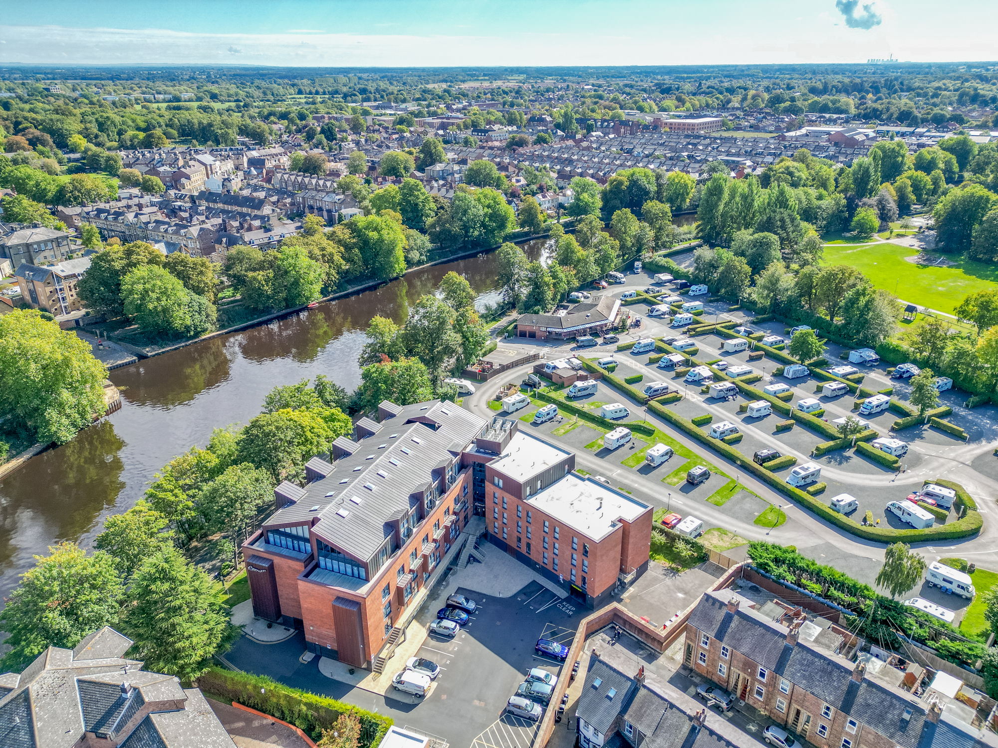 Scenic riverside stay with parking, greenery, and sweeping aerial views