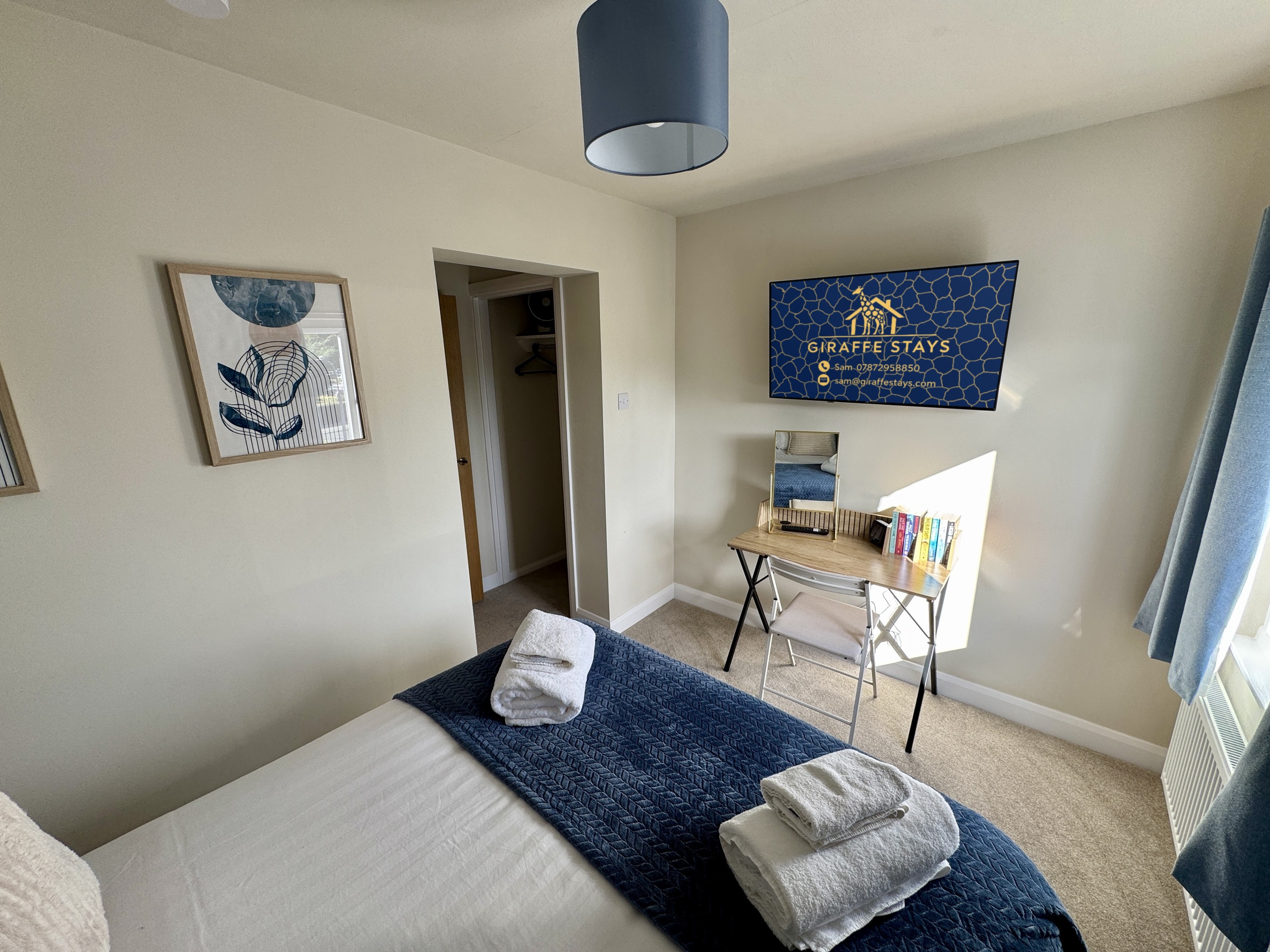 Bright, cozy bedroom with workspace, fresh linens, and stylish blue accents