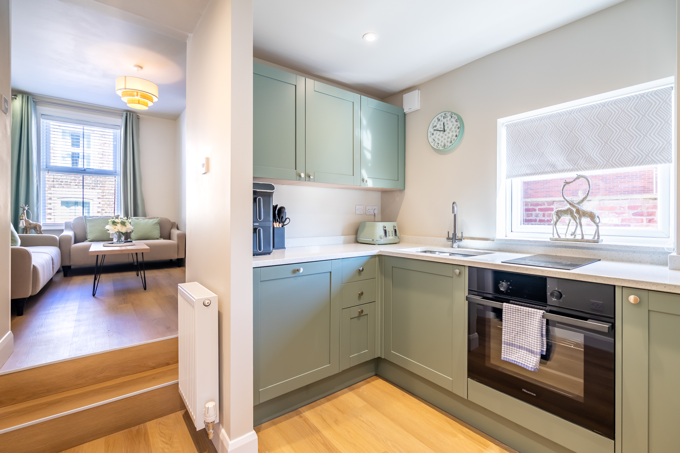 Bright sage-green kitchen with modern finishes and open living flow