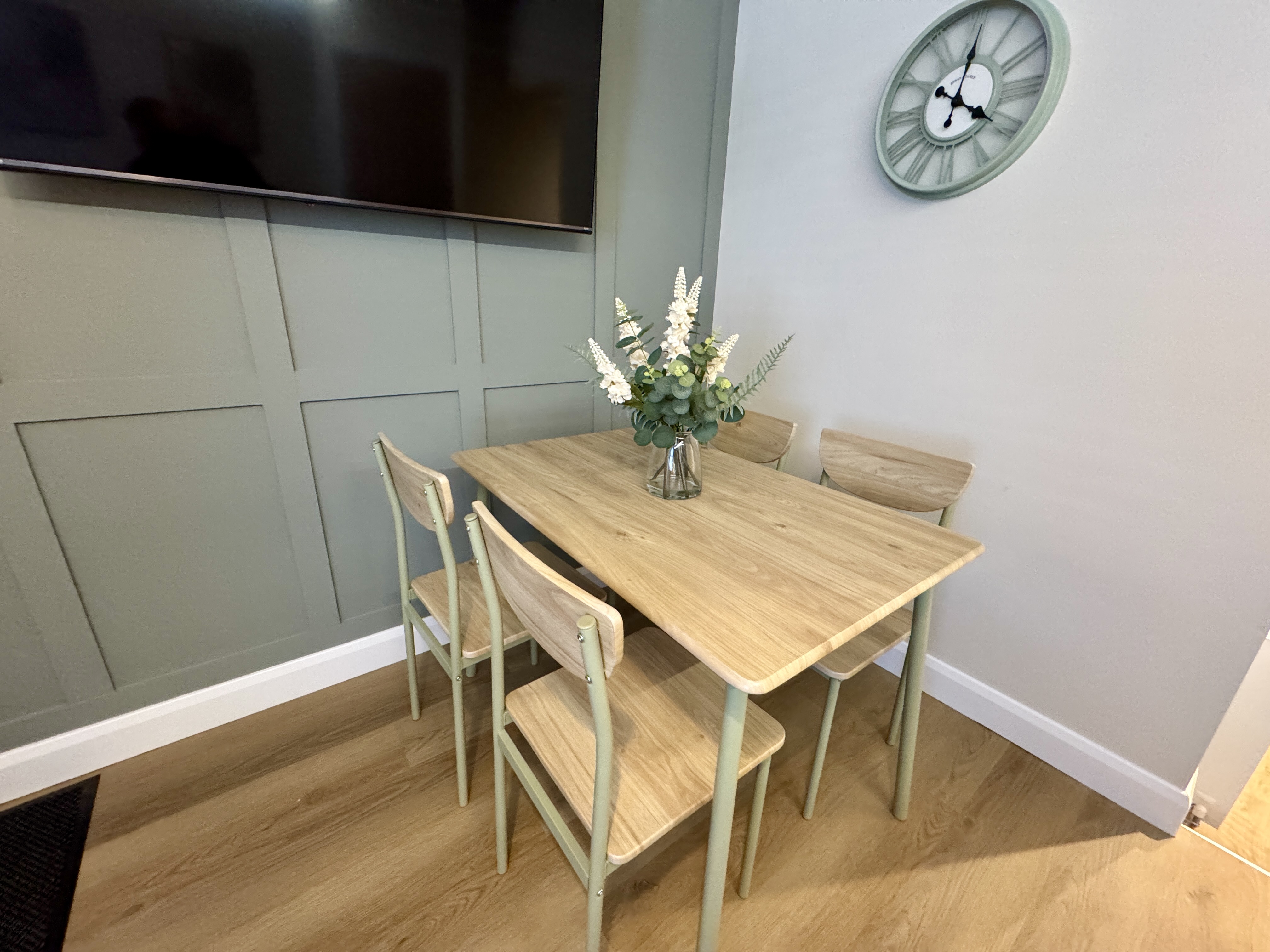 Cozy modern dining nook with TV, stylish paneling, and seating for four