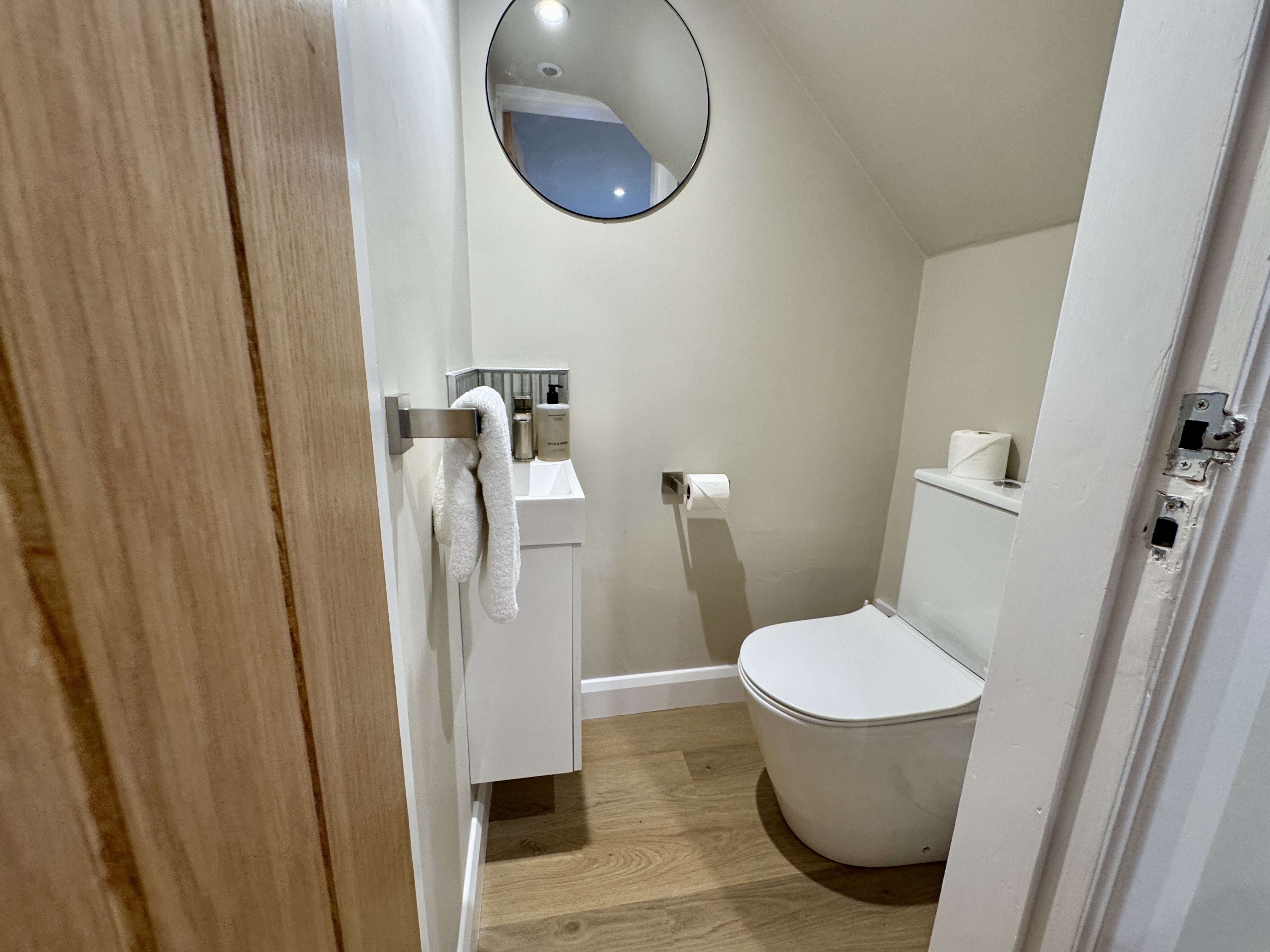 Modern compact bathroom with sleek finishes and warm wood-style flooring