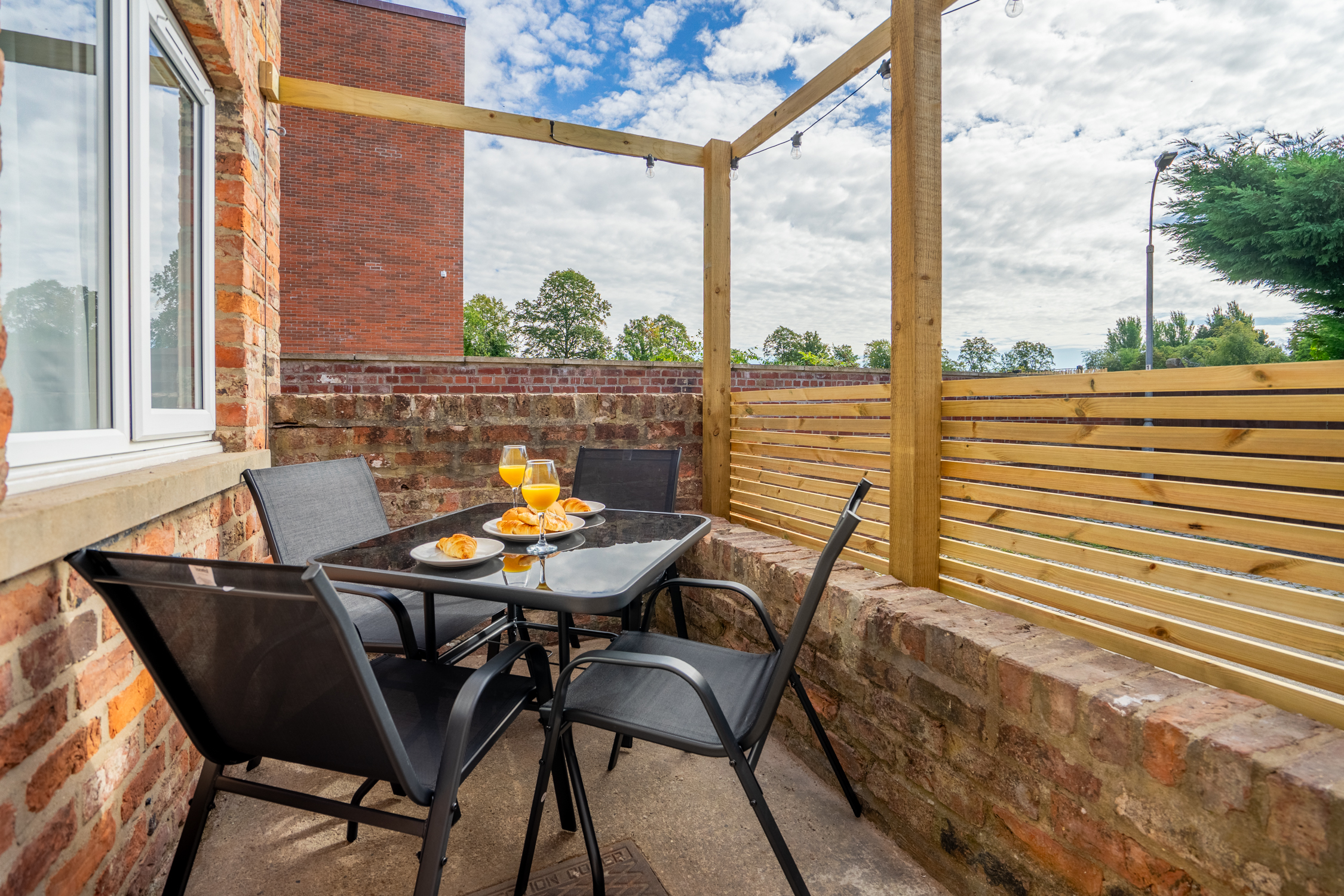 Private brick patio with outdoor dining, privacy screens & string lights