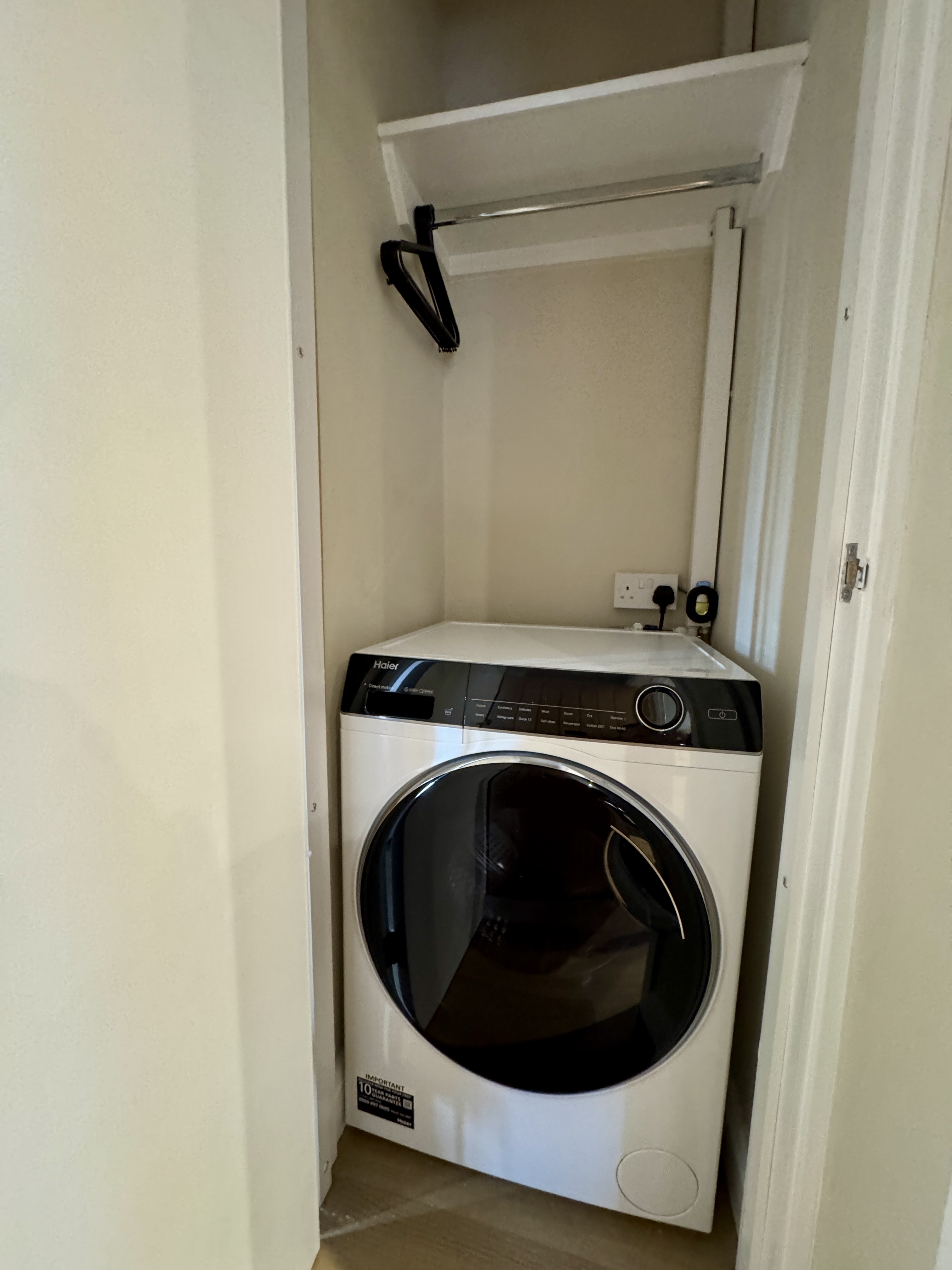 Convenient in-unit laundry with storage shelf and hanging rod