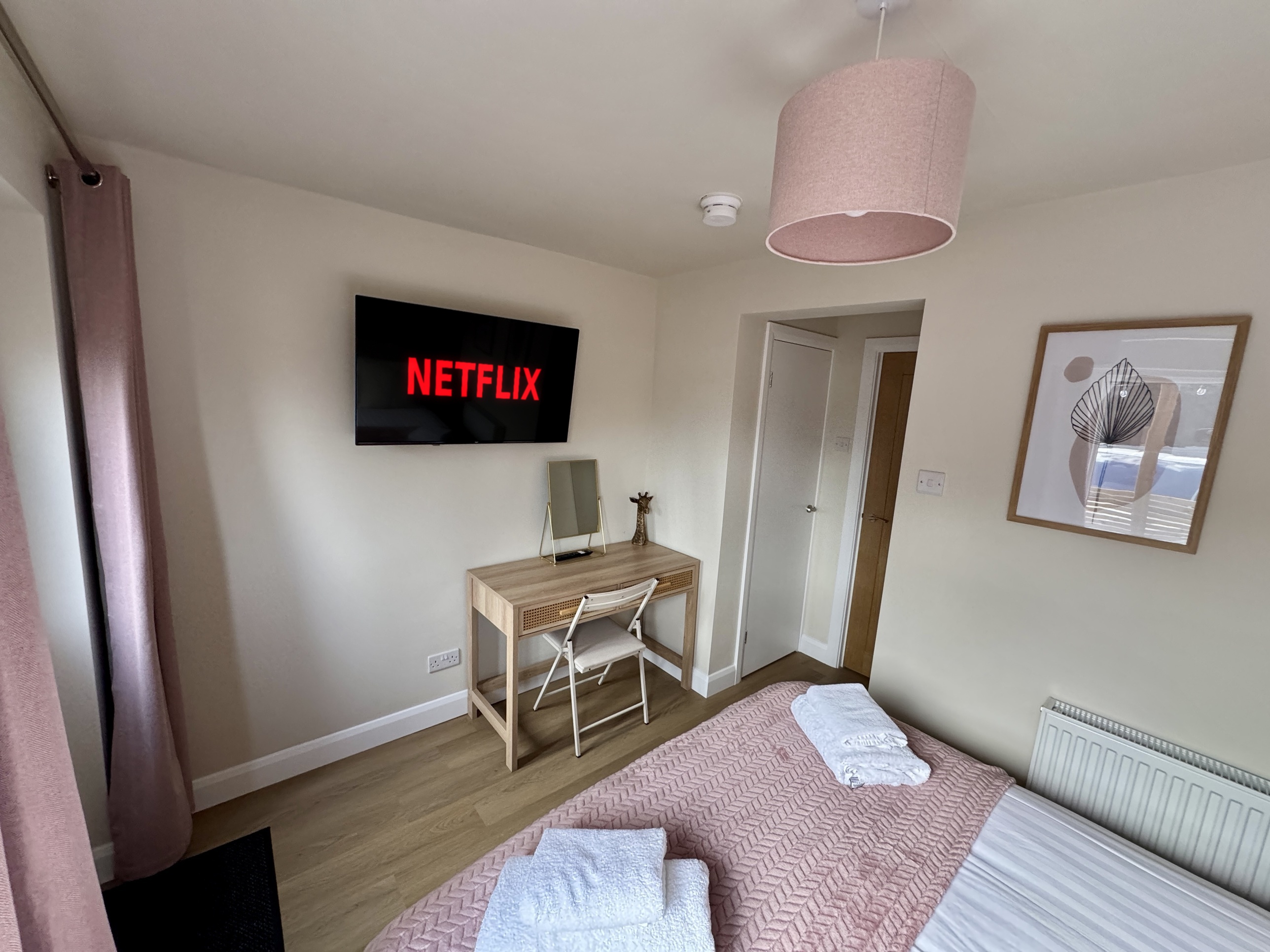 Bright modern bedroom with Netflix TV, desk, and soft blush decor