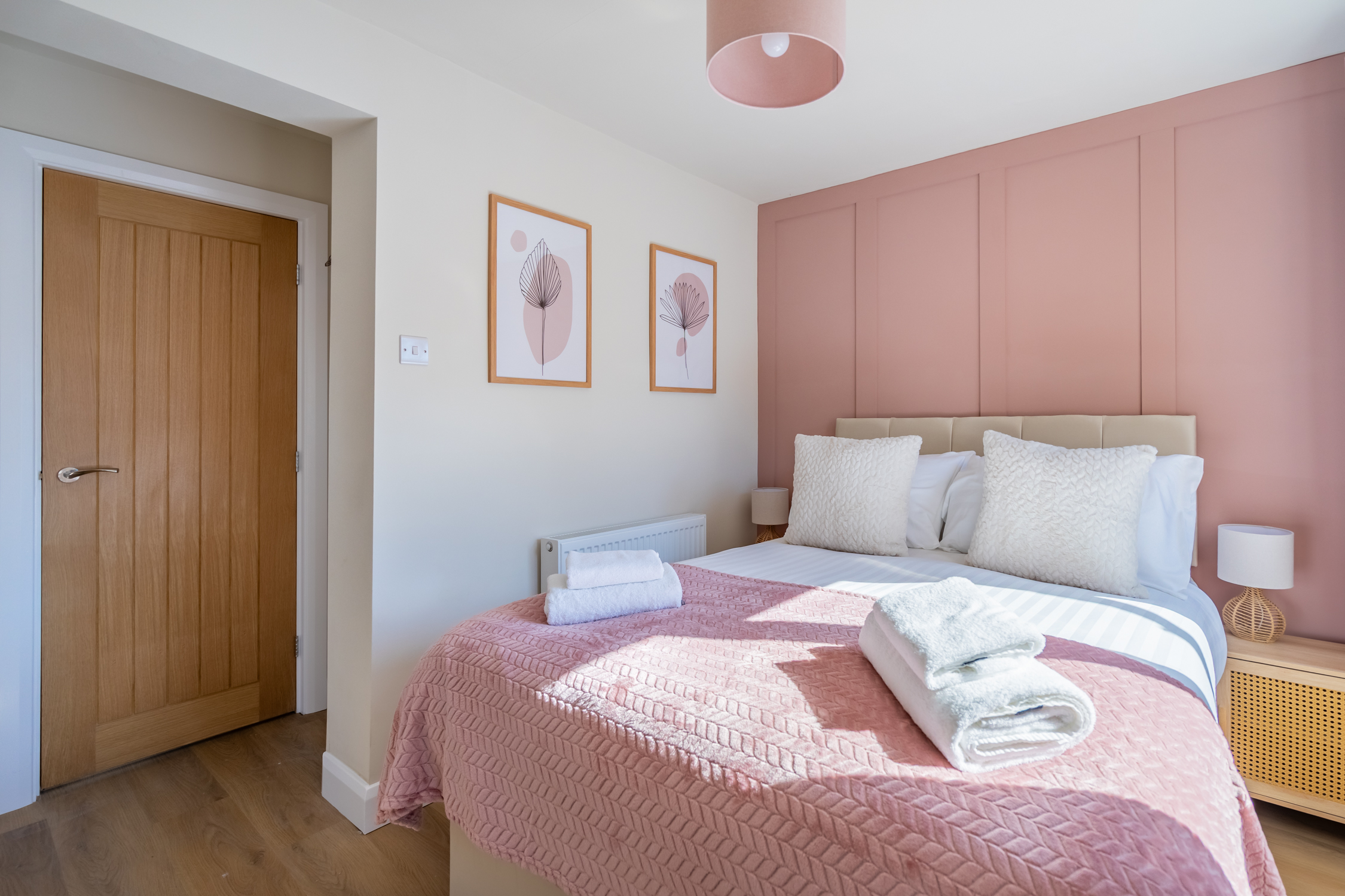 Stylish pink-accent bedroom with fresh towels and a bright, cozy feel