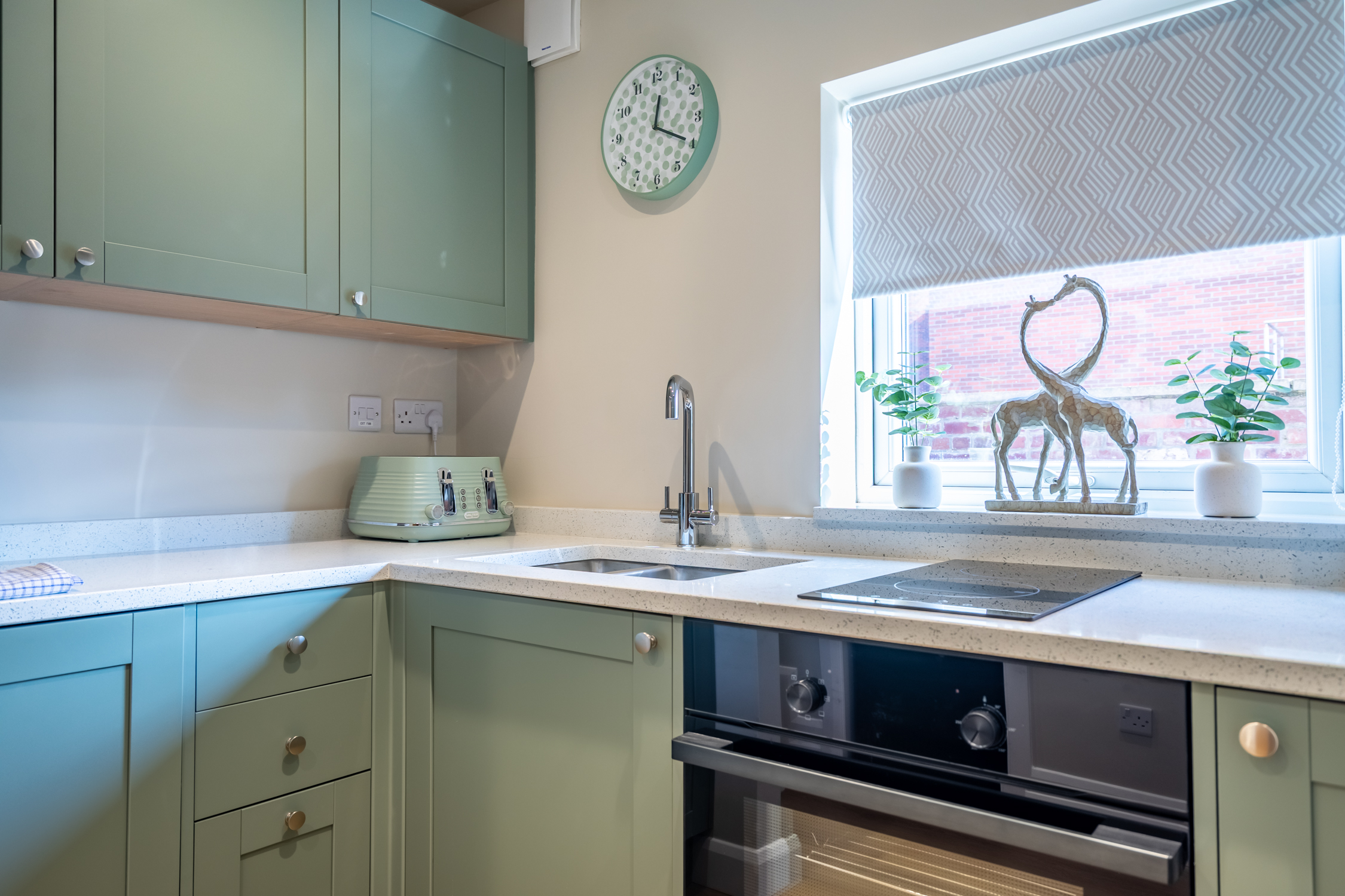Bright modern kitchen with sage cabinets, natural light, and stylish décor
