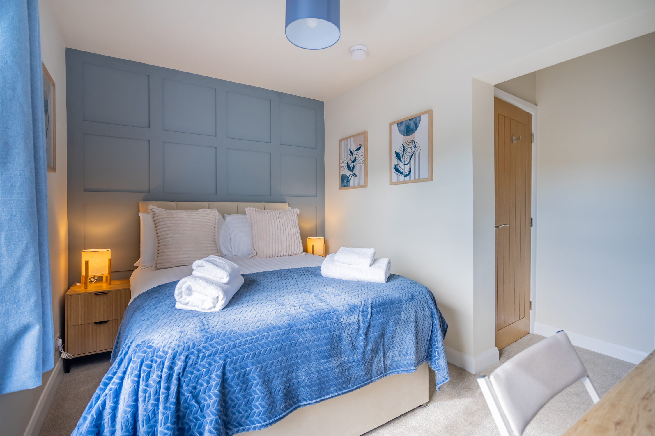 Stylish blue-accent bedroom with plush linens and warm bedside lighting