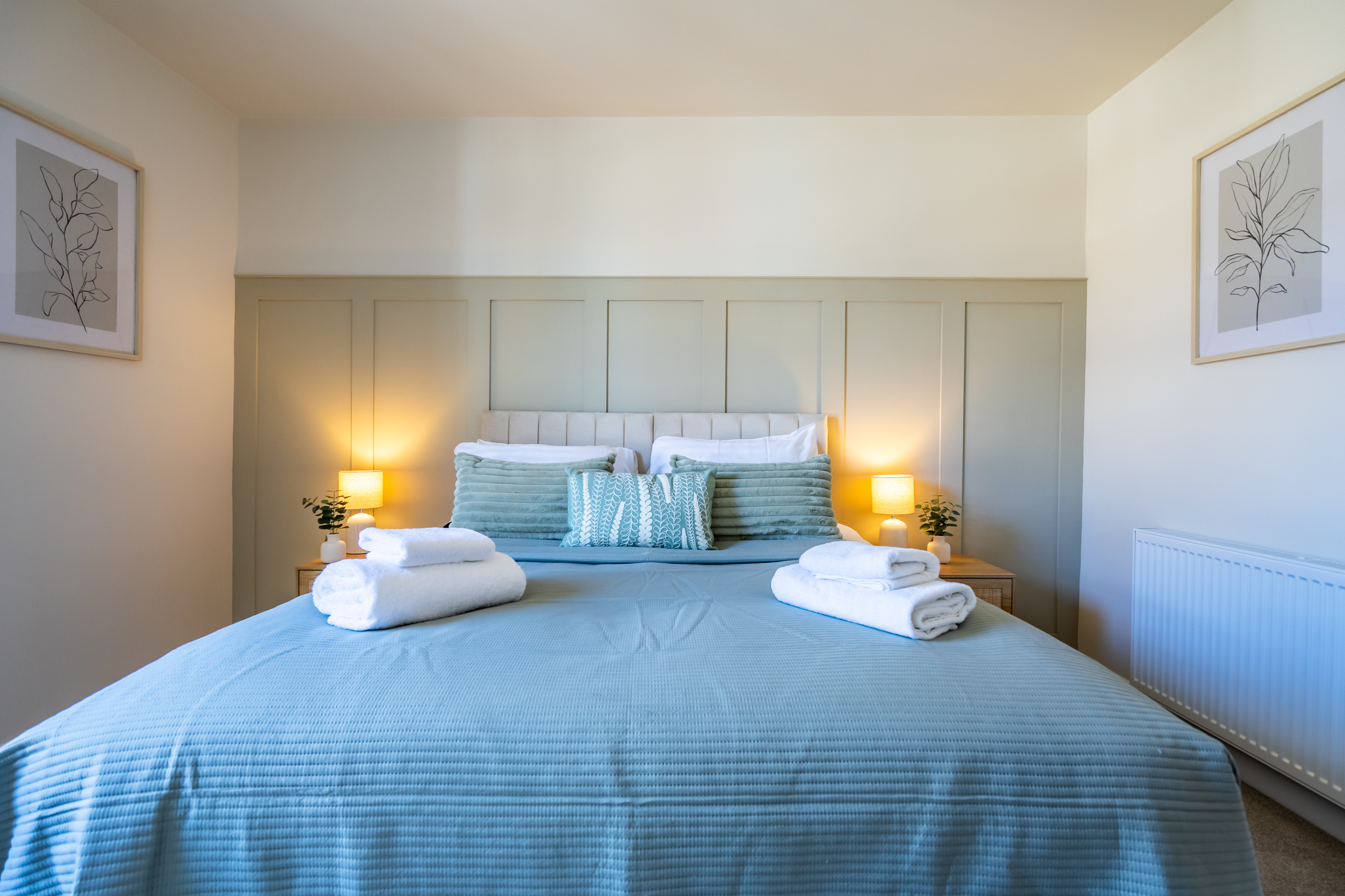Calm, stylish bedroom with plush bedding and warm bedside lighting