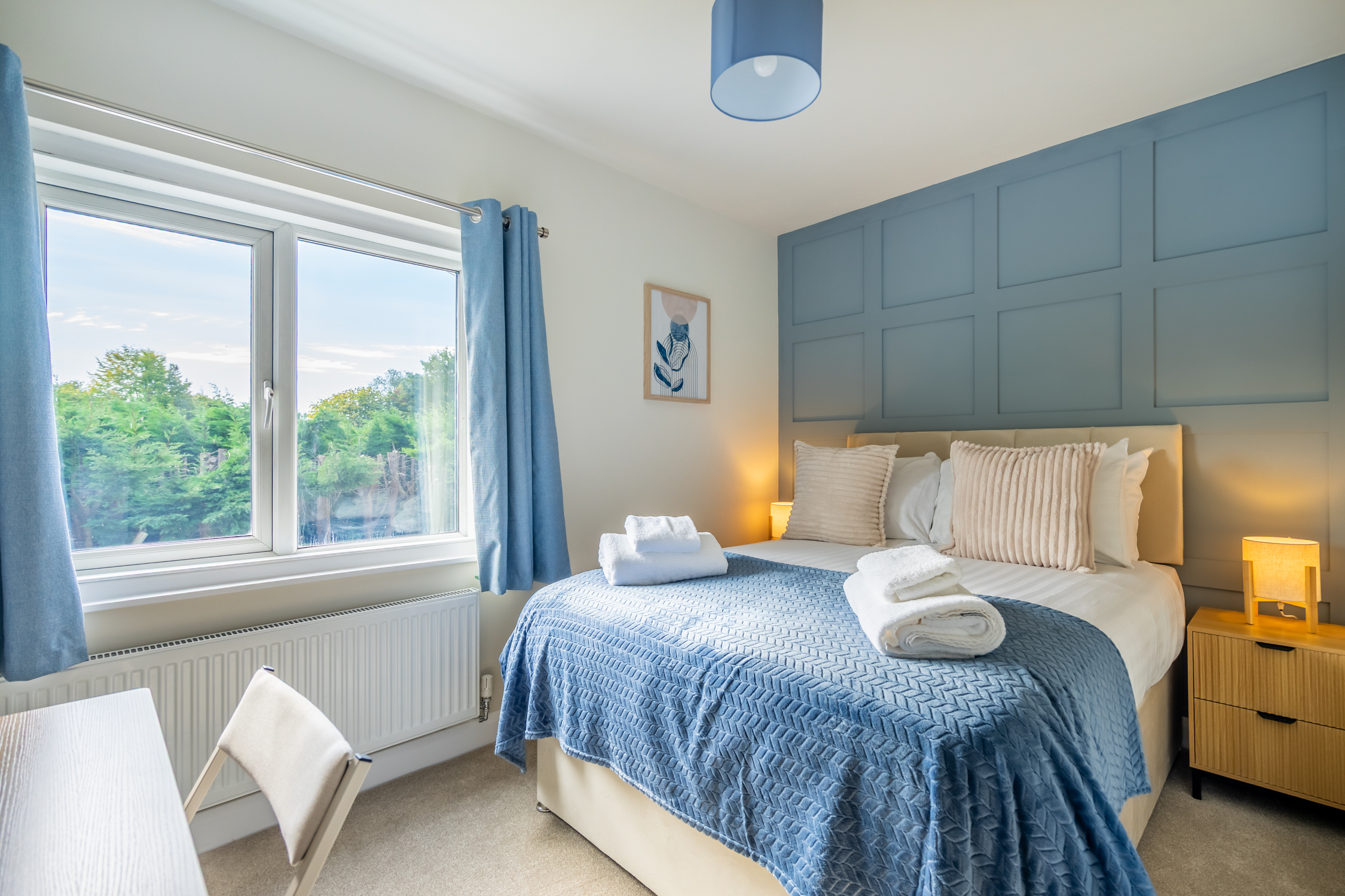 Bright blue-toned bedroom with garden views and a cozy, stylish finish