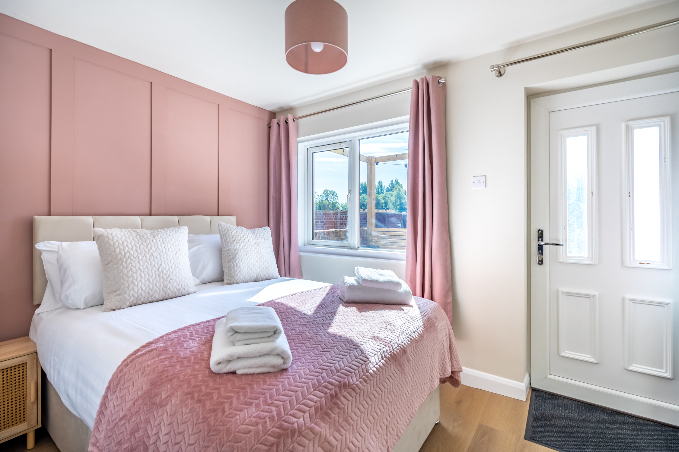 Bright, cozy bedroom with blush accents, natural light, and private entry