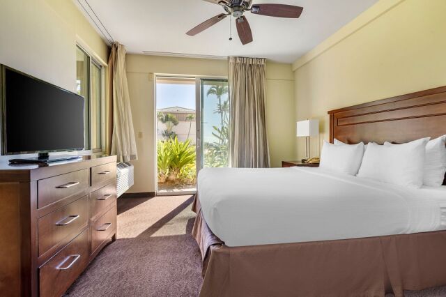 Bright king bedroom with garden-view patio doors and warm wood accents