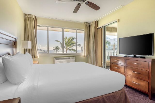 Bright tropical bedroom with balcony access and palm tree views