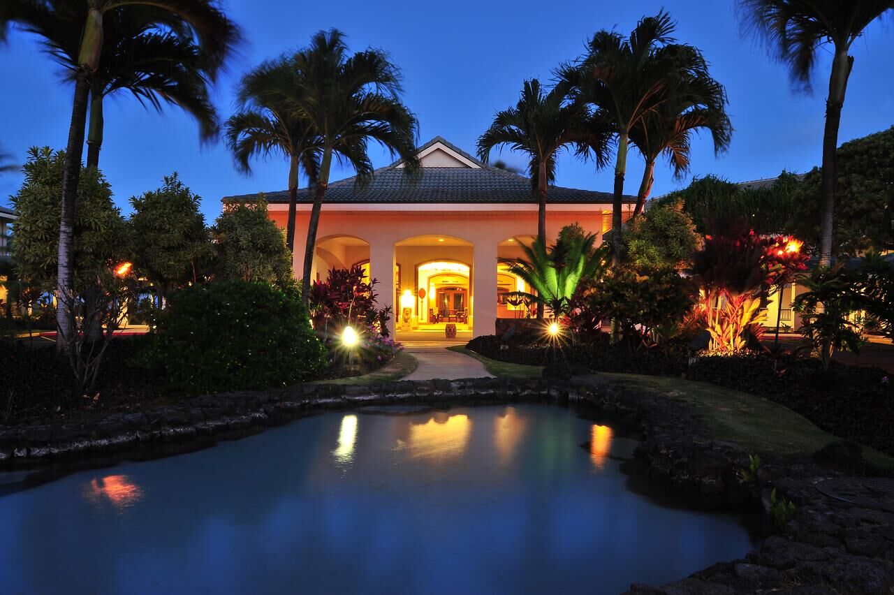 Tropical villa entrance with glowing lights, palms, and tranquil pond