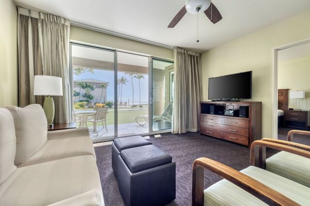 Bright living room with patio access and serene palm-lined water views