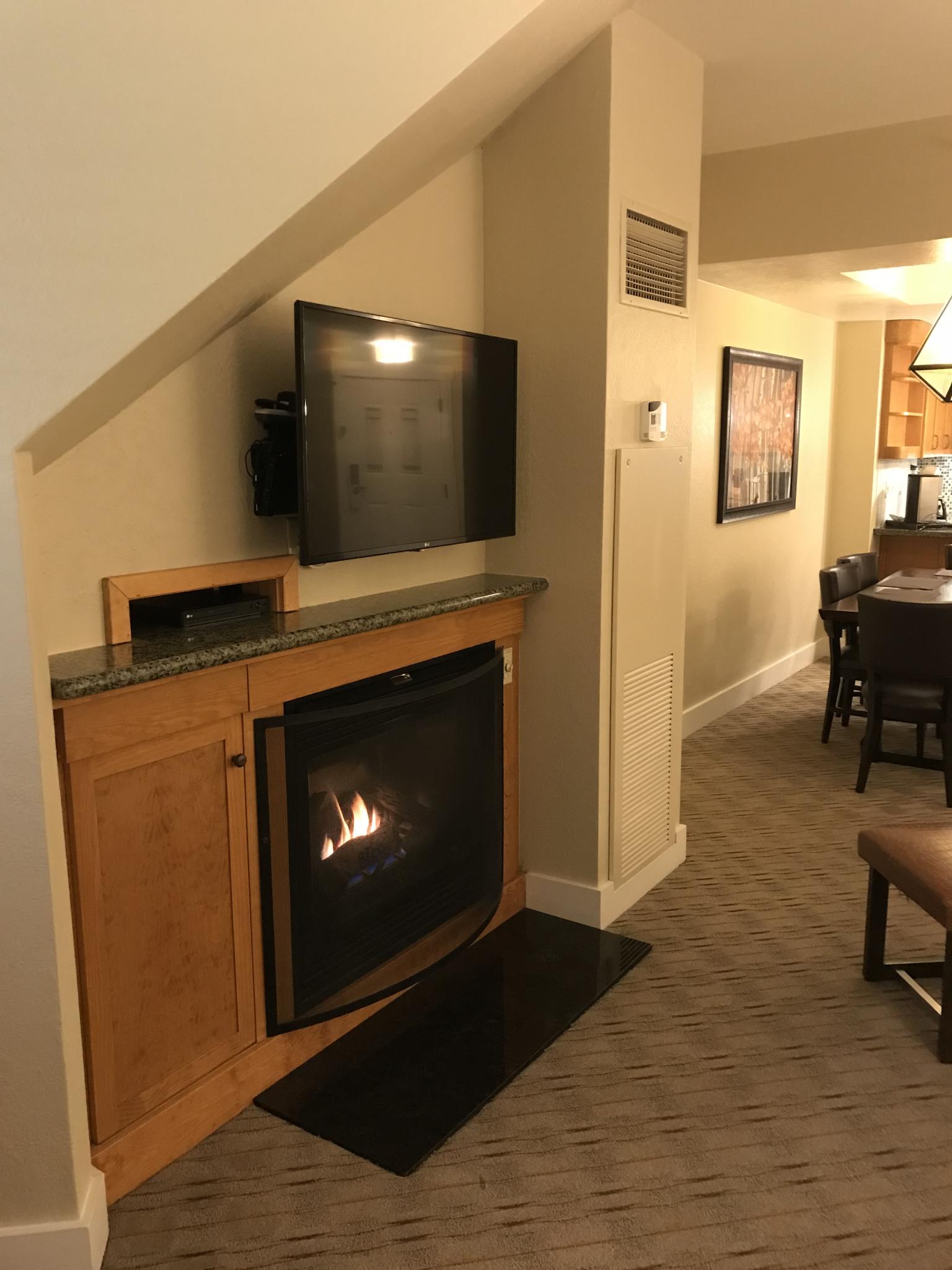 Cozy fireplace lounge with wall-mounted TV and open dining area
