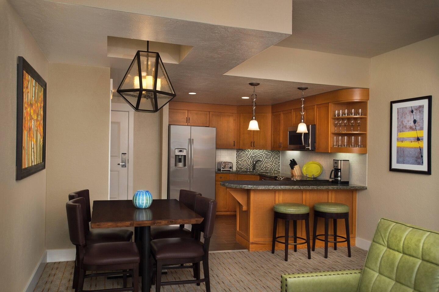 Warm open kitchen with breakfast bar, dining table, and modern finishes