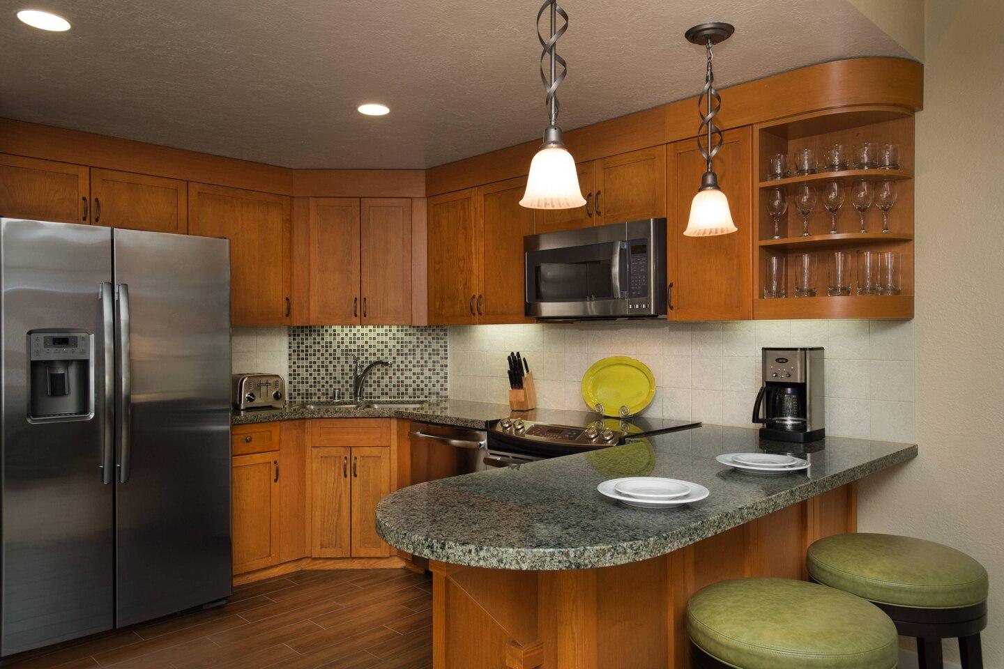 Warm gourmet kitchen with granite bar seating and stainless appliances