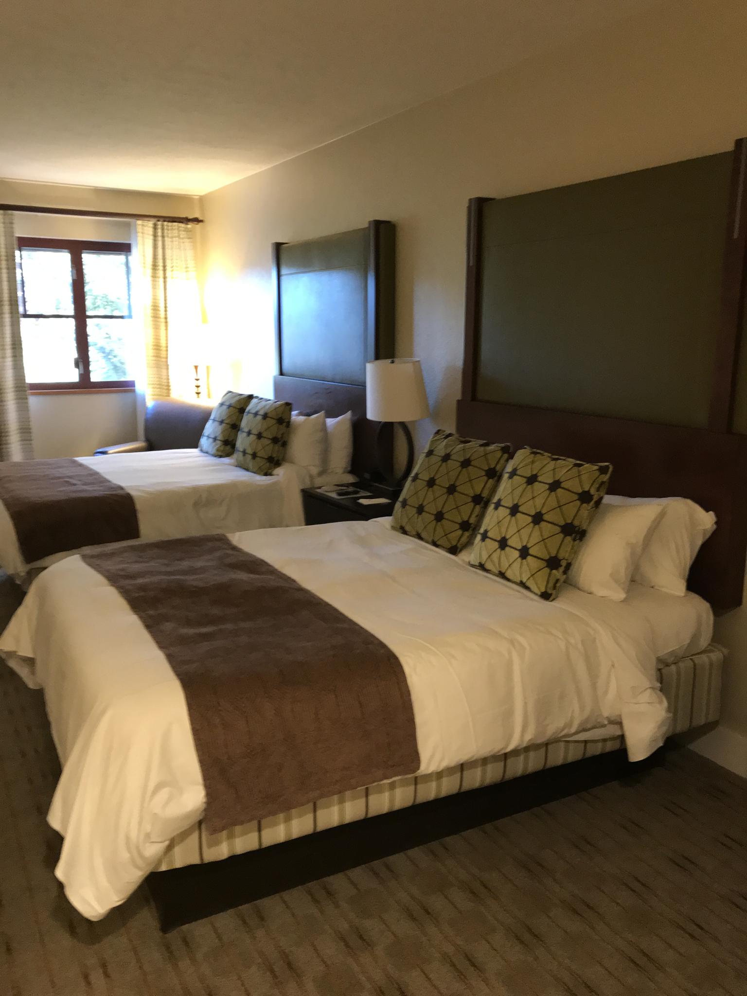 Comfortable double-queen room with warm decor and natural light