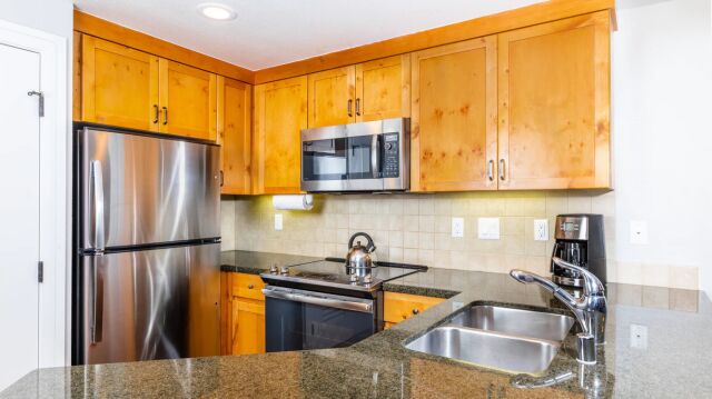 Bright kitchen with granite counters, stainless appliances, and warm wood cabinets
