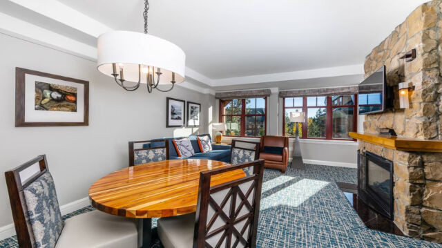 Bright mountain-style living space with stone fireplace and sunny dining area