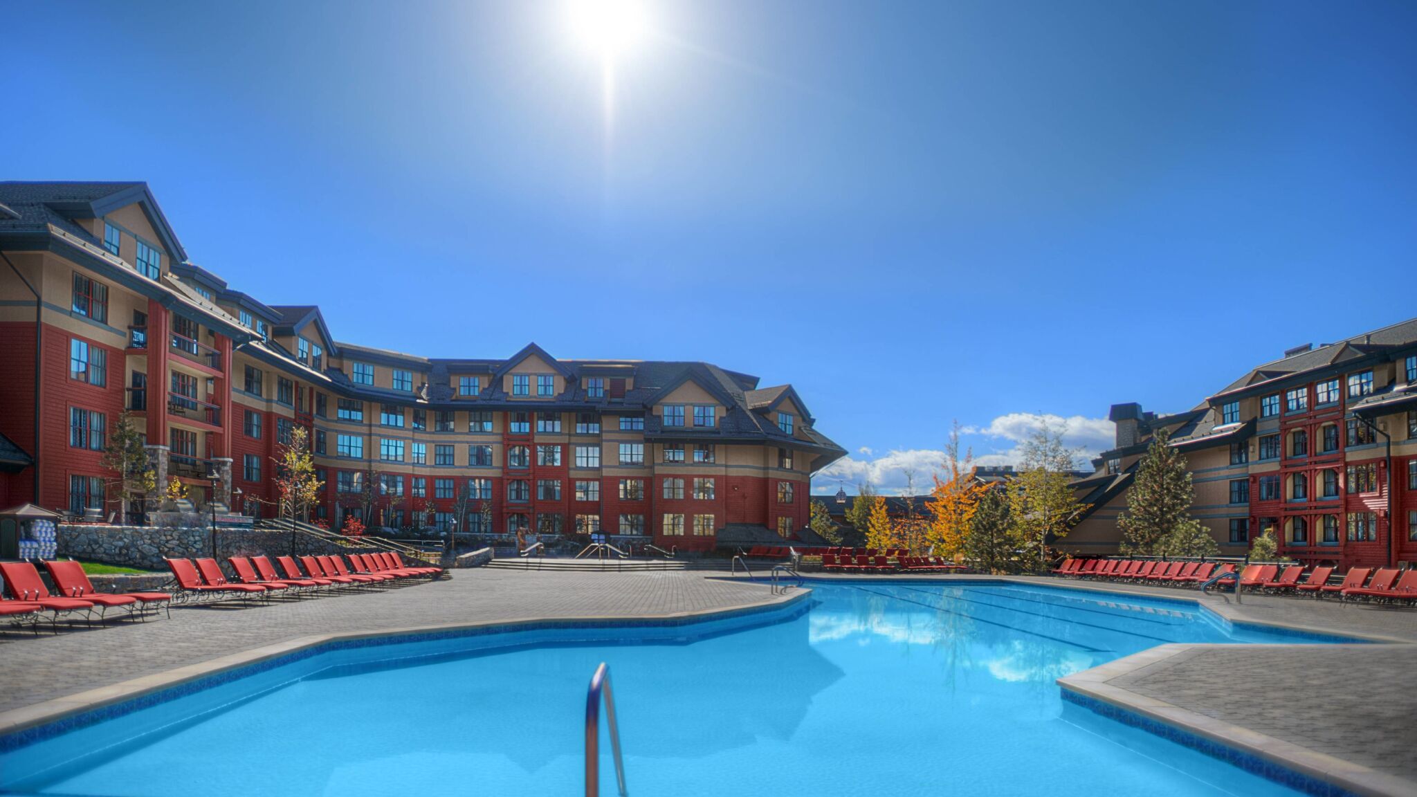 Sunny resort-style outdoor pool with spacious deck and lounge seating