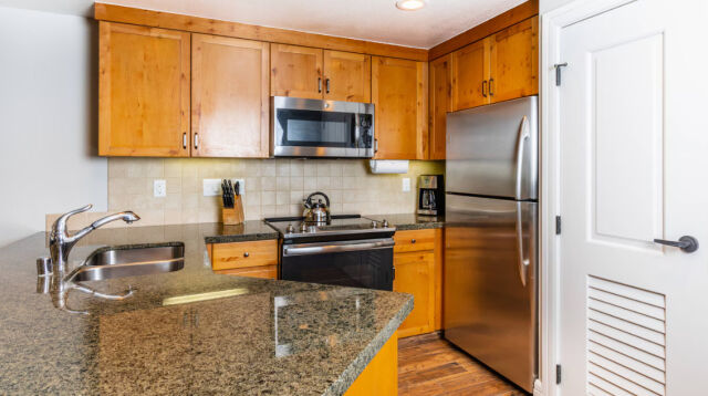 Warm wood kitchen with granite counters and stainless steel appliances